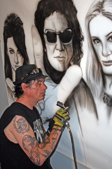 Artist Paul Archer works on his latest project: a mural of rock star Gene Simmons and family that he presented to them at an event held last weekend.